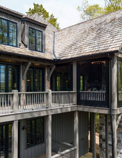 A house with a balcony overlooking a wooded area.