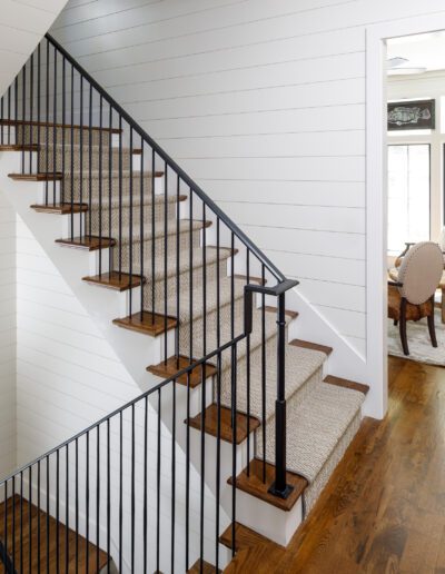 A staircase in a white house with black railings.