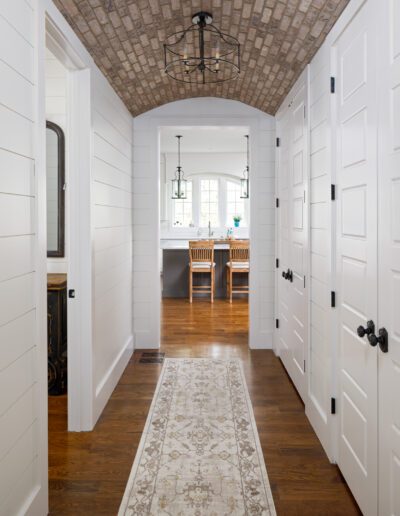 A hallway with white walls and a rug.