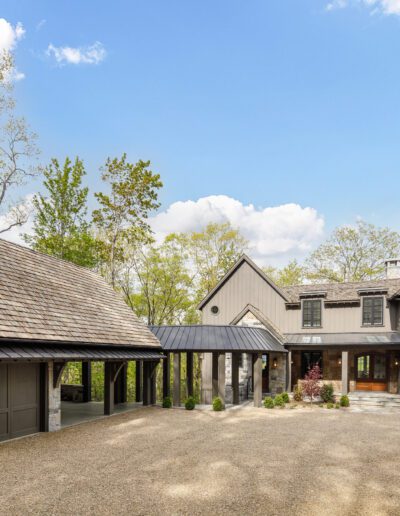 A home in the woods with a driveway and garage.