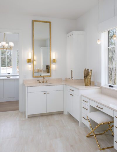 A white and gold bathroom with a glass shower.