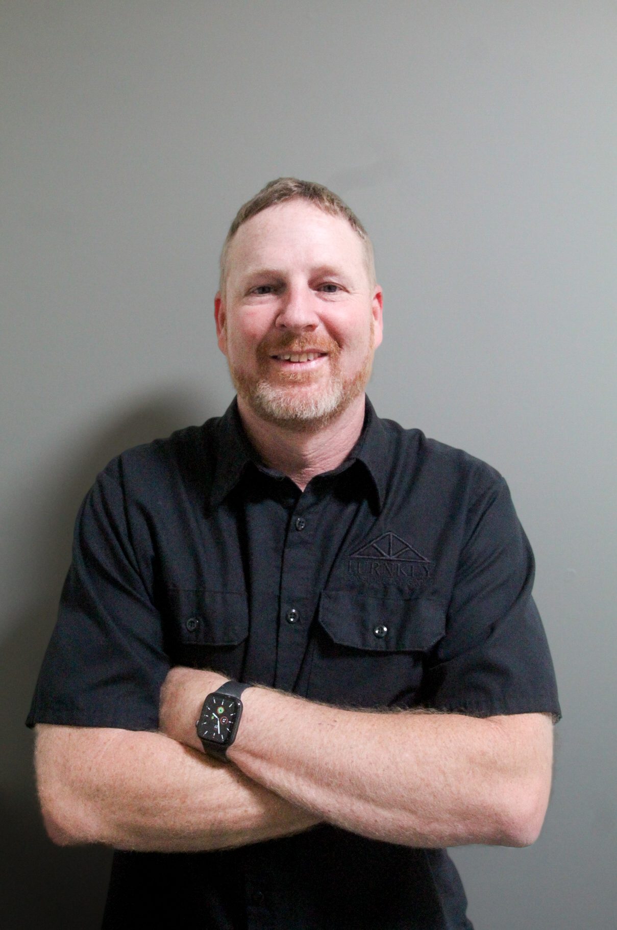 A man in a black shirt with his arms crossed.